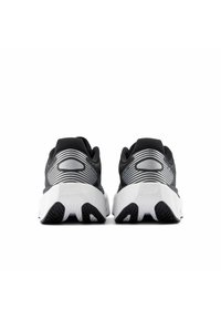 Chaussures de sport noires avec un dessus texturé et des rayures argentées, présentant une semelle intermédiaire blanche et une semelle extérieure noire pour l'adhérence.