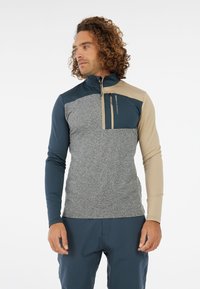 Fleece pullover met een halve rits kraag, gekenmerkt door marineblauwe, beige en grijze kleurvakken. Opvallende voorzak en gestructureerde stof.