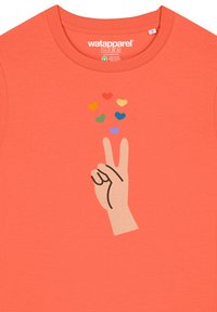 Koraalkleurig T-shirt met een afbeelding van een hand die een vredesteken maakt, omringd door kleurrijke hartvormen in rood, blauw, geel, groen en paars.