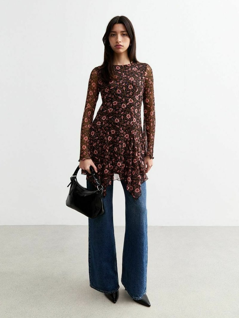 Top lungo a maniche lunghe nera con motivo floreale e bordo svasato, abbinato a jeans blu a gamba larga con vita alta e una borsa nera. Tessuto morbido.