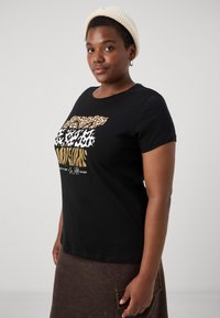 Juodas medvilninis marškinėliai su apvalia kaklo iškirpte ir trumpomis rankovėmis, dekoruoti sluoksniuotais gyvūnų raštais auksinės, rudos ir juodos spalvų.