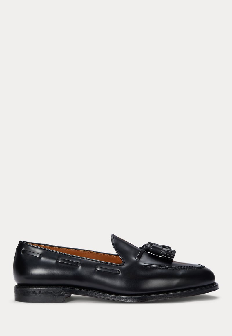 Zwarte leren loafer met kwastdetail en lage hak, zijaanzicht tegen een effen achtergrond.