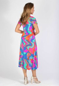 Monivärinen mekko joustavasta materiaalista, jossa on aaltoilevia kuvioita sinisellä, vaaleanpunaisella, vihreällä ja oranssilla. Keskipitkä malli, jossa on lyhyet hihat ja levenevä helma.
