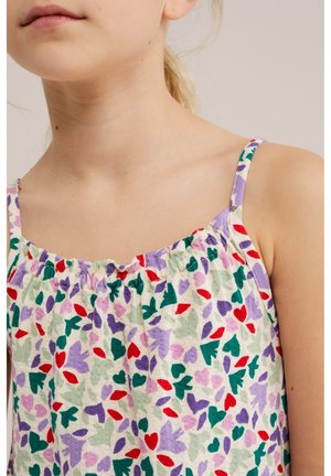 Laps kannab varrukateta pluusi kogutud kaelusega, millel on lilla, roheline, punane ja lavendli südame- ja lehemuster valgel taustal.