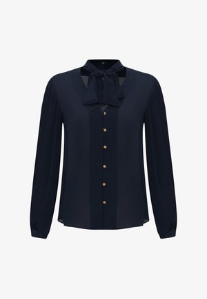 Námořnická modrá blůza s krčním vázáním, zapínáním na knoflíky a nařasenými rukávy. Vyrobená z hladké tkaniny s zlatými knoflíky jako akcenty.