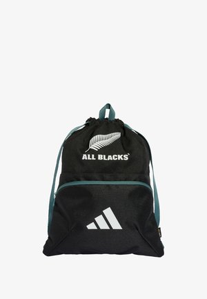 Mochila negra con cordón, fabricada en un tejido duradero, que cuenta con una cinta de acento verde, impresiones de logotipos y un bolsillo frontal con cremallera.