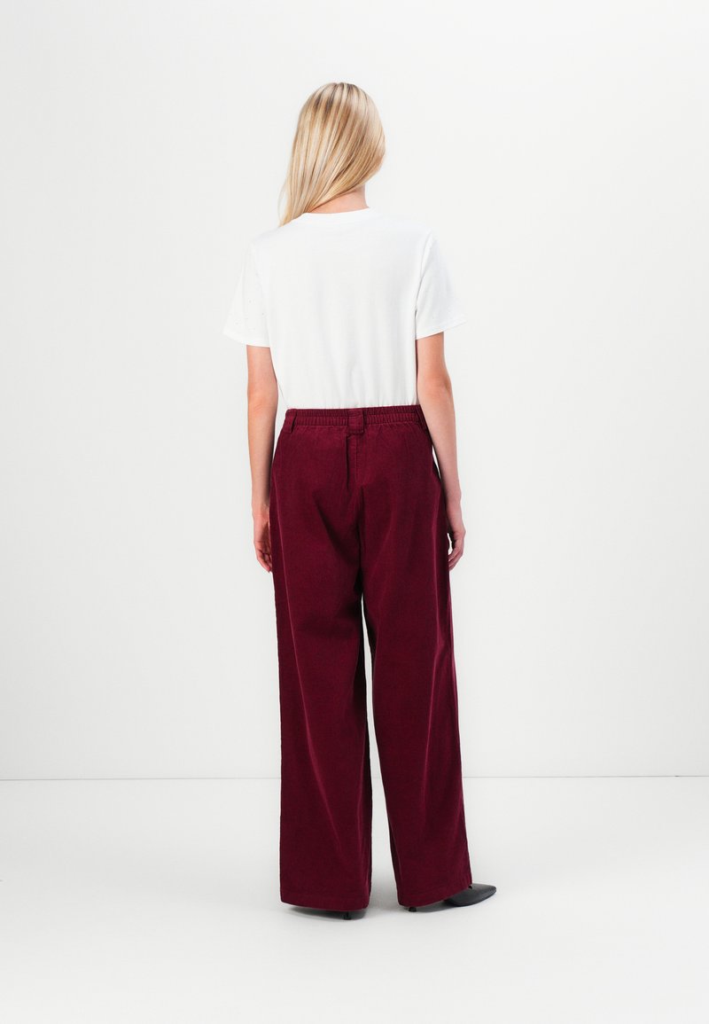 T-shirt bianco a maniche corte abbinato a pantaloni larghi bordeaux con vita elastica e design a gamba dritta.