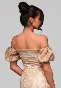 Off-the-shoulder beige klänning med rosormönster, strukturerad tyg och puffärmar. Har en figurnära silhuett och dold dragkedja i ryggen.