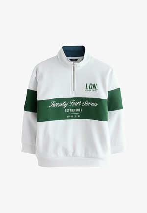 Baltas džemperis su žalia horizontalia juosta, ketvirčio užtrauktuko apykakle ir užrašu „LDN. 51.5229°N 0.0777°W“ bei „Twenty Four Seven Established Since 1982“