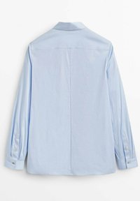 Vue de dos d'une chemise unie bleu clair à manches longues avec col et poignets boutonnés sur fond blanc.