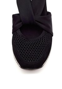 Bailarinas negras con la puntera de malla de un patrón texturizado, parte superior de tela suave y un diseño de correa anudada para un ajuste seguro.