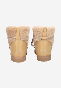Bottines beige en cuir et fausse fourrure avec un col duveteux, bout rond et petit talon. "Inuikii" embossé à l'arrière.