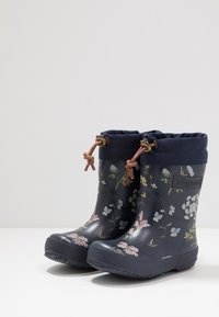 Bottes de pluie en caoutchouc navy avec un motif floral, dotées d'un col en tissu bleu et de lacets marron. Semelles texturées pour une meilleure adhérence.
