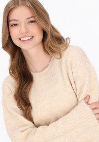 Beige gestrickter Pullover mit lockerer Passform, strukturiertem Oberflächen und subtilen Pailletten. Verfügt über breite Ärmel und einen runden Ausschnitt.
