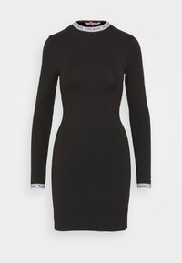 Vestido negro de manga larga con cuello alto. Presenta un collar y puños acanalados con la marca "Tommy Jeans". Fabricado con un tejido suave y elástico.