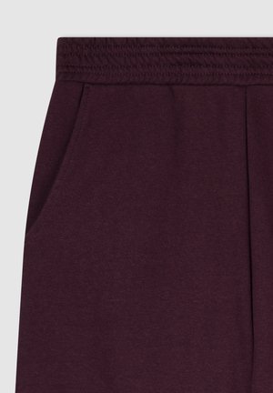 Pantaloni della tuta bordeaux con una texture morbida, cintura elastica e tasche laterali. Presentano un design pulito senza motivi visibili o elementi metallici.