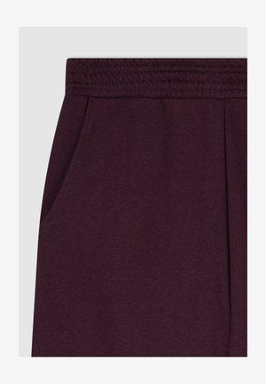 Pantaloni della tuta bordeaux con una texture morbida, cintura elastica e tasche laterali. Presentano un design pulito senza motivi visibili o elementi metallici.