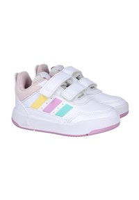 Zapatillas deportivas blancas con tiras de velcro, con franjas acentuadas en amarillo pastel, rosa y azul, y una lengüeta de malla texturizada. Suela rosa.