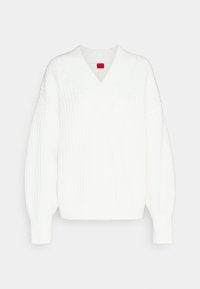 Pull en tricot blanc avec un col en V, coupe oversize, texture côtelée et manches longues. Présente des détails de motifs subtils.