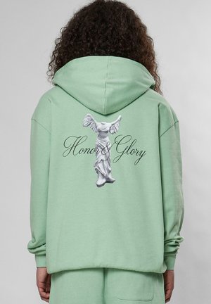 Mintgrøn hættebluse med snorhue, udsmykket med et hvidt trykt statueskabelon og teksten "Honor & Glory" på ryggen. Fremstillet af bomuldsmateriale.