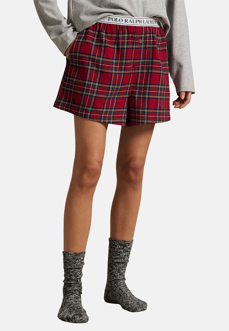Punaiset ruutukuvioiset shortsit, joissa on nappikiinnitys ja joustava vyötärönauha, jossa lukee "POLO RALPH LAUREN". Yhdistetty teksturoiduihin harmaisiin sukkiin.