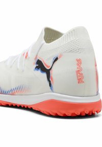 Puma-kengät valkoisena monivärisillä yksityiskohdilla. Ominaisuuksia ovat teksturoitu päällinen, pyöreä kärki ja vaaleanpunainen pohja. Logo näkyy sivussa.