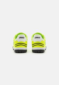 Scarpe da ginnastica giallo neon con accenti neri, tomaia in rete, collare imbottito e suola in gomma testurizzata per una buona aderenza. Logo "JAKO" sul tallone.