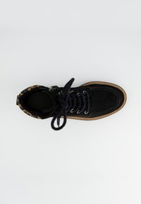 Bottines en suede noir avec une doublure en imprimé léopard. Comprend des lacets ronds, des œillets en métal et une semelle texturée. Fermeture éclair sur le côté.