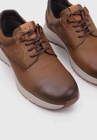 Zapatos de cuero marrón con cordones, de textura suave, puntera redondeada, suela blanca acolchada y acentos marrones en el parte superior que contrastan.