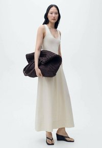 Robes sans manches beige clair, tombant jusqu'aux chevilles. Sac tissé marron foncé avec une poignée, surface texturée. Tongs compensées noires.
