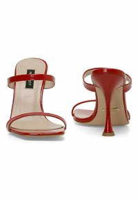 Red patent leather high heels with a sleek design, featuring two thin straps across the foot and a stiletto heel. Smooth interior lining.
