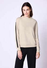 Beige mikina s kulatým výstřihem a dlouhými rukávy, s černými bočními pruhy a žebrovaným lemem. Hladká tkanina s volným střihem.