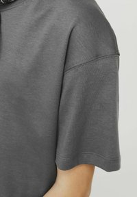 T-shirt in cotone grigio con vestibilità comoda, maniche corte e cuciture visibili lungo il colletto e l'orlo.