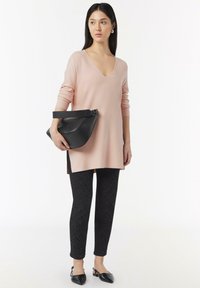 Light pink long-sleeve top with a V-neck, paired with black textured pants featuring a zebra pattern and black pointed-toe shoes.
