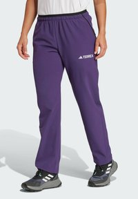 Paarse Terrex-broek heeft een relaxte pasvorm, een elastische tailleband en witte logo-details. Het materiaal is glad met een lichte textuur.