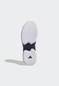 Sole of a sneaker featuring a white rubber surface with textured grip, dark navy accents, and visible branding with "TORSION SYSTEM" details.