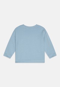 Vaalean sininen pitkähihaisuus paita, jossa on pyöreä pääntie, pehmeä rakenne ja ribbed hihansuut. Siinä on lyhennetty muotoilu suoran helman kanssa.