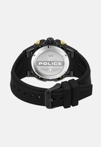 Orologio con cinturino in gomma nera, retro in acciaio inossidabile argentato, dettagli dorati e un motivo dettagliato sul quadrante che presenta la parola "POLICE."