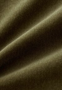 Olijfgroen stof met een zachte, gestructureerde afwerking met subtiele ribbels. Het materiaal lijkt warm en zacht, wat comfort aangeeft.