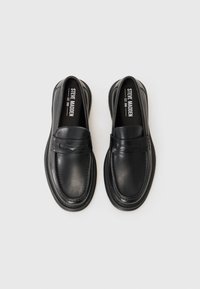 Scarpe slip-on in pelle nera con punta arrotondata, cuciture decorative e suola in gomma a profilo basso. Presentano un piccolo dettaglio con una striscia sulla parte superiore.