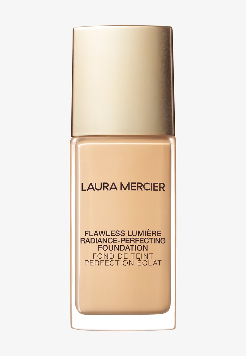 Beżowa szklana butelka podkładu z złotą nakrętką. Czarny tekst brzmi "Flawless Lumière Radiance-Perfecting Foundation." Gładka tekstura.
