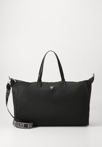 Sac de voyage en nylon noir avec des accents en cuir, deux poignées supérieures, une sangle d'épaule ajustable, quincaillerie en argent et un détail de logo triangulaire.