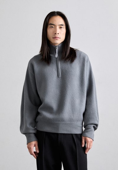 Grauer Fleece-Pullover mit hohem Kragen und halbem Reißverschluss. Verfügt über gerippte Bündchen und Saum, lockere Passform und weiche Textur.