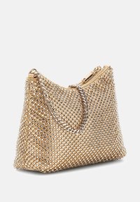 Borsa beige con design a rete decorata con borchie argento, tracolla a catena e chiusura a zip nella parte superiore. Texture liscia.