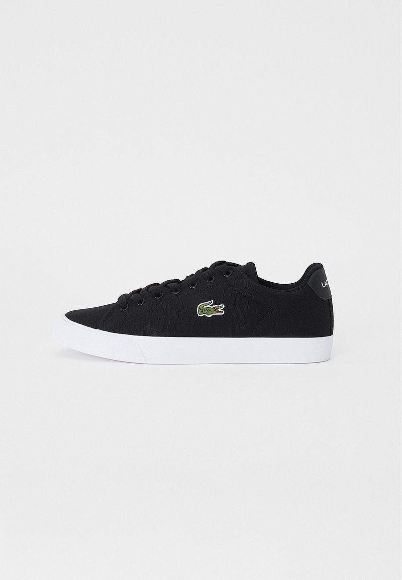 Sneakers neri in tela con suole bianche in gomma, dotati di un logo ricamato verde sul lato e lacci neri tondi.