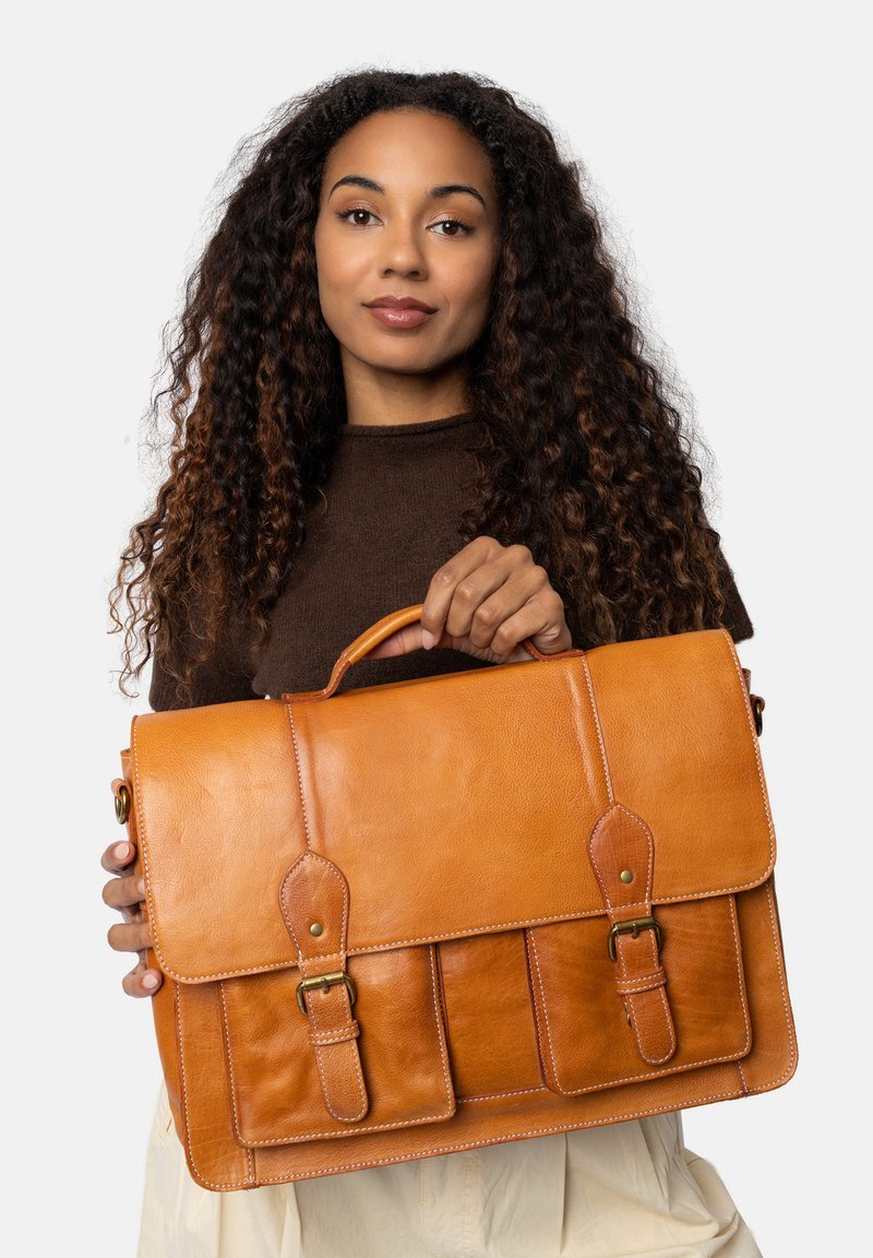 Valigetta in pelle marrone con due tasche frontali, manico regolabile e hardware in ottone. Texture liscia e accenti cuciti in tutto il prodotto.