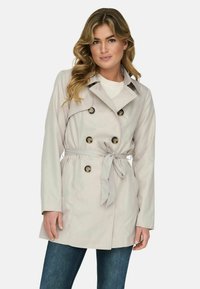 Helebeež trench coat topelt nööpide ja vöödiga, millel on klassikaline krae ja pikad varrukad.