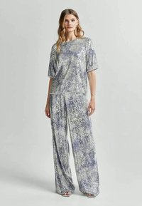 Zilveren pailletten twee-delig outfit met een loszittende top en wijdvallende broek, met een gestructureerd oppervlak en een ontspannen silhouet.
