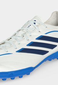 Λευκό και μπλε ποδοσφαιρικό παπούτσι Adidas με κορδόνια, τρεις σκούρες μπλε ρίγες στο πλάι και μπλε αγκράφες στη σόλα.