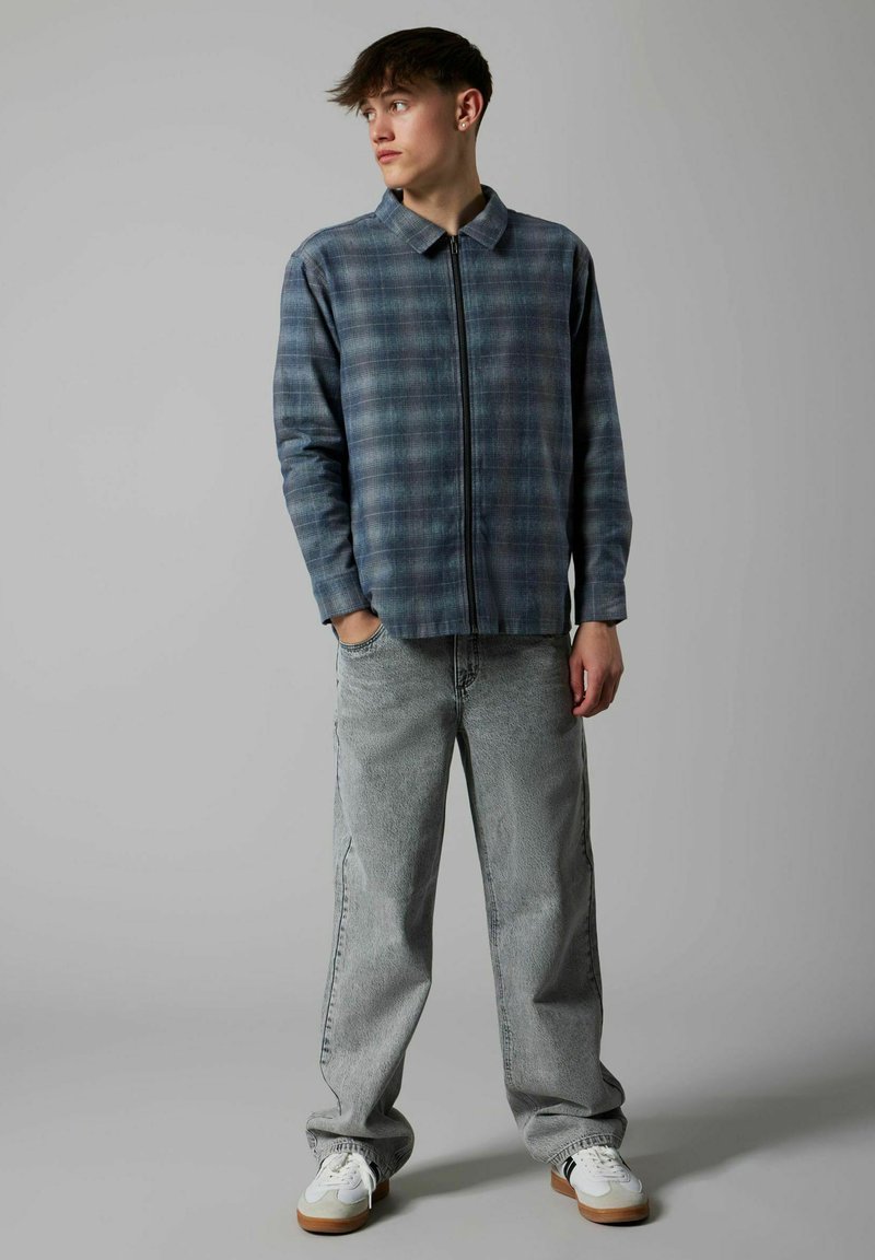 Sinine-hall ruuduline poollukuga särk, kombineeritud helehallide lahtiste teksade ja valgete tossudega, millel on pruunid detailid.